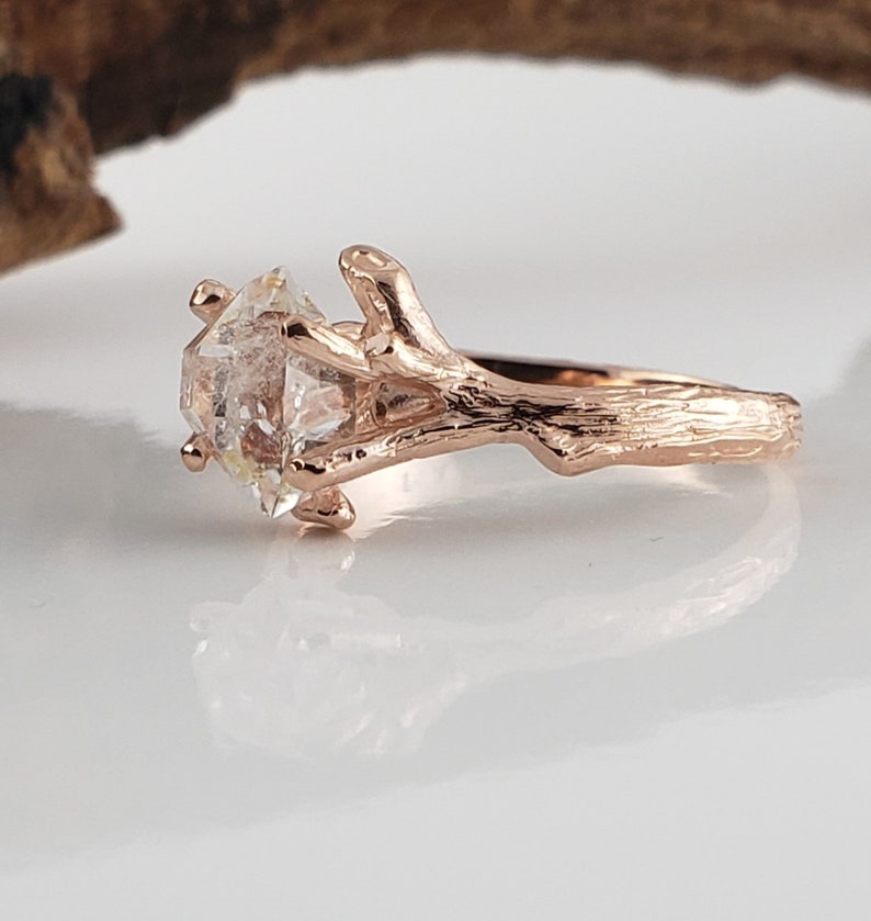 Rose gold ring with a diamond on a white surface