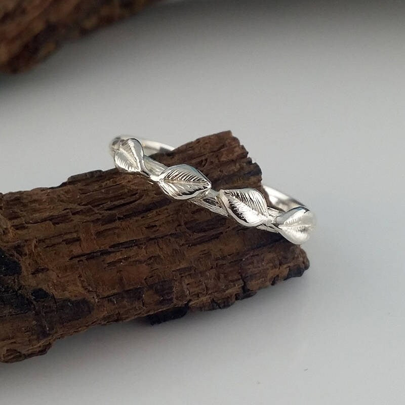 Silver ring with leaf design on a wooden surface