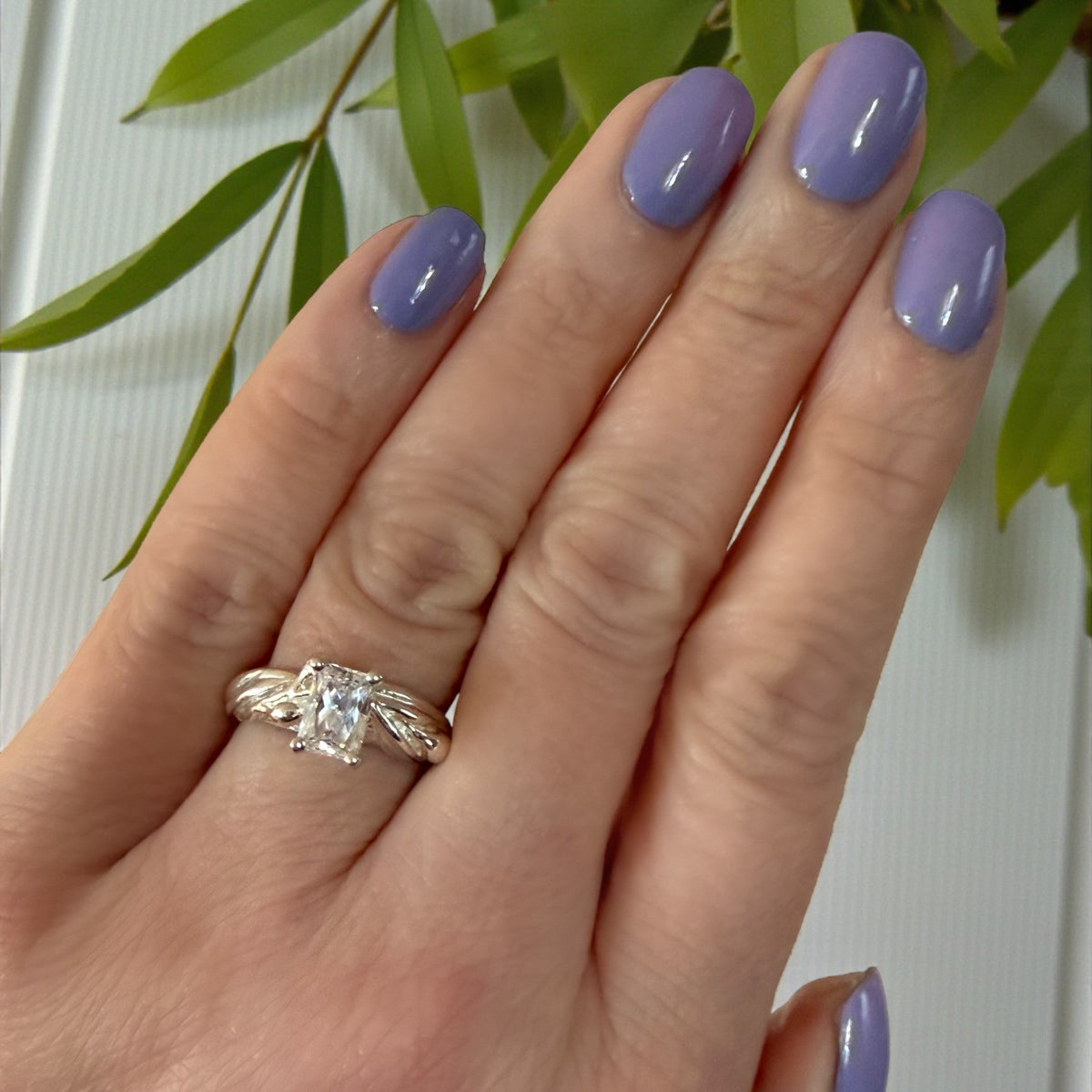 rectangle shaped moissanite diamond in white gold on a hand with a hand-sculpted olive leaves as the setting