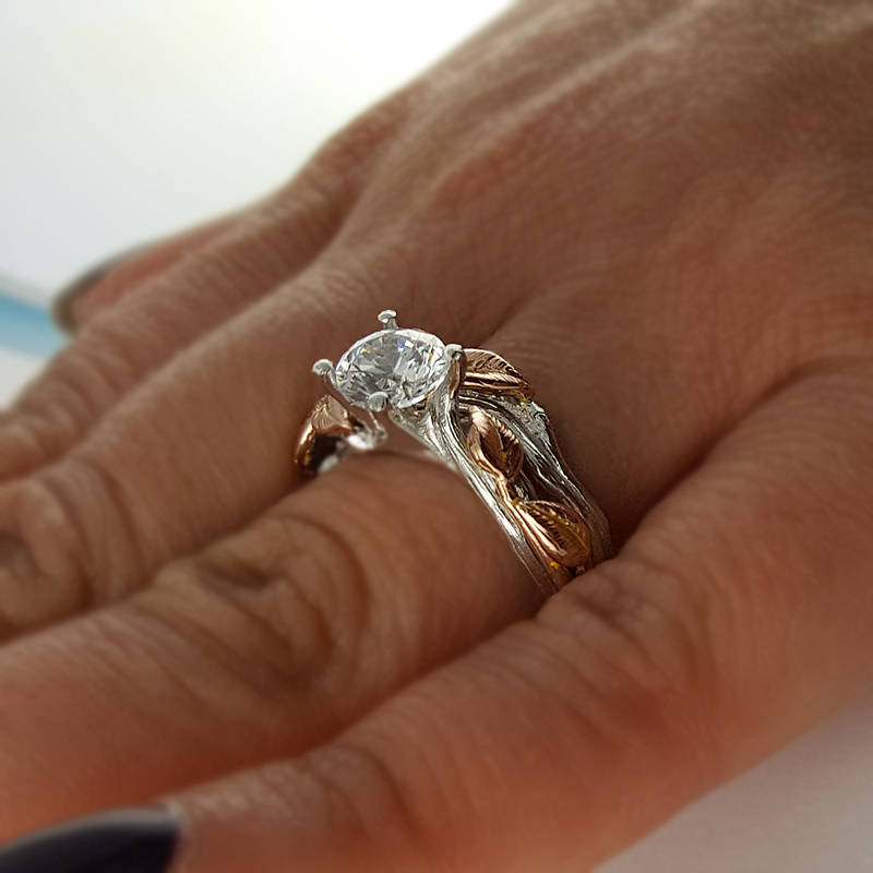 round moissanite diamond ring with white and rose gold design of leaves