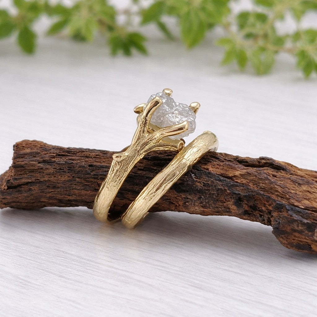 Gold ring with a diamond on a wooden branch against a light background