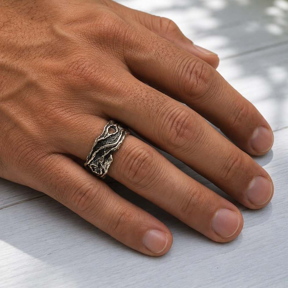 Hand wearing a silver driftwood style ring on a light wooden surface