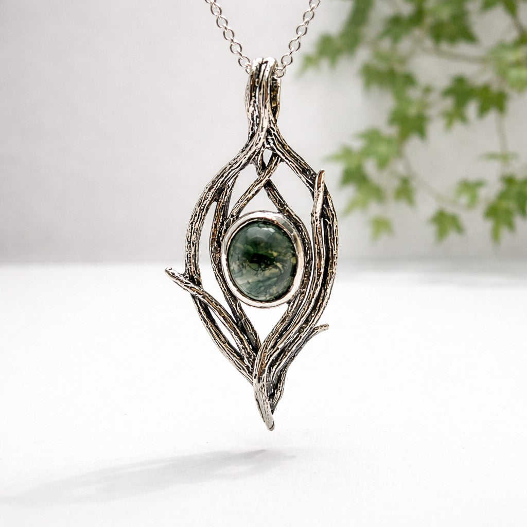 Silver pendant with green stone on a white background - handmade sterling silver twig and branch design pendant with a round moss agate stone in the middle.