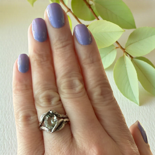 shiny green amethyst gemstone ring in sterling silver on a hand with leaves wrapped around the stone
