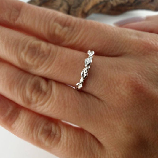 Silver leaf ring on a person's finger with a neutral background