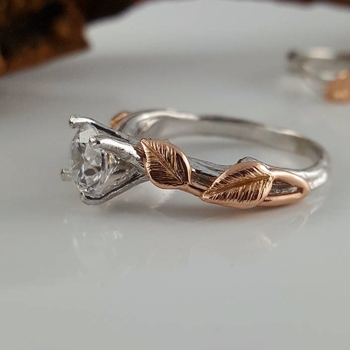 Silver ring with rose gold leaves on a white surface