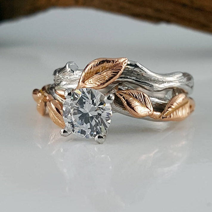 Two rings with leaf designs and a central diamond on a white surface