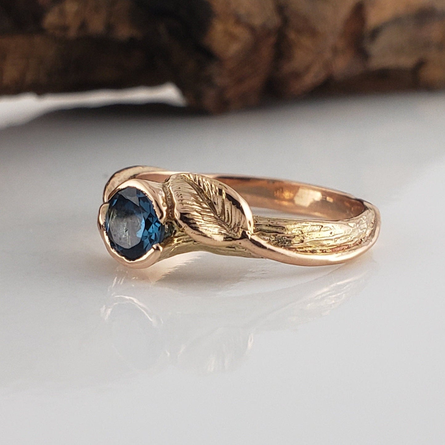 Gold ring with a blue gemstone on a white surface