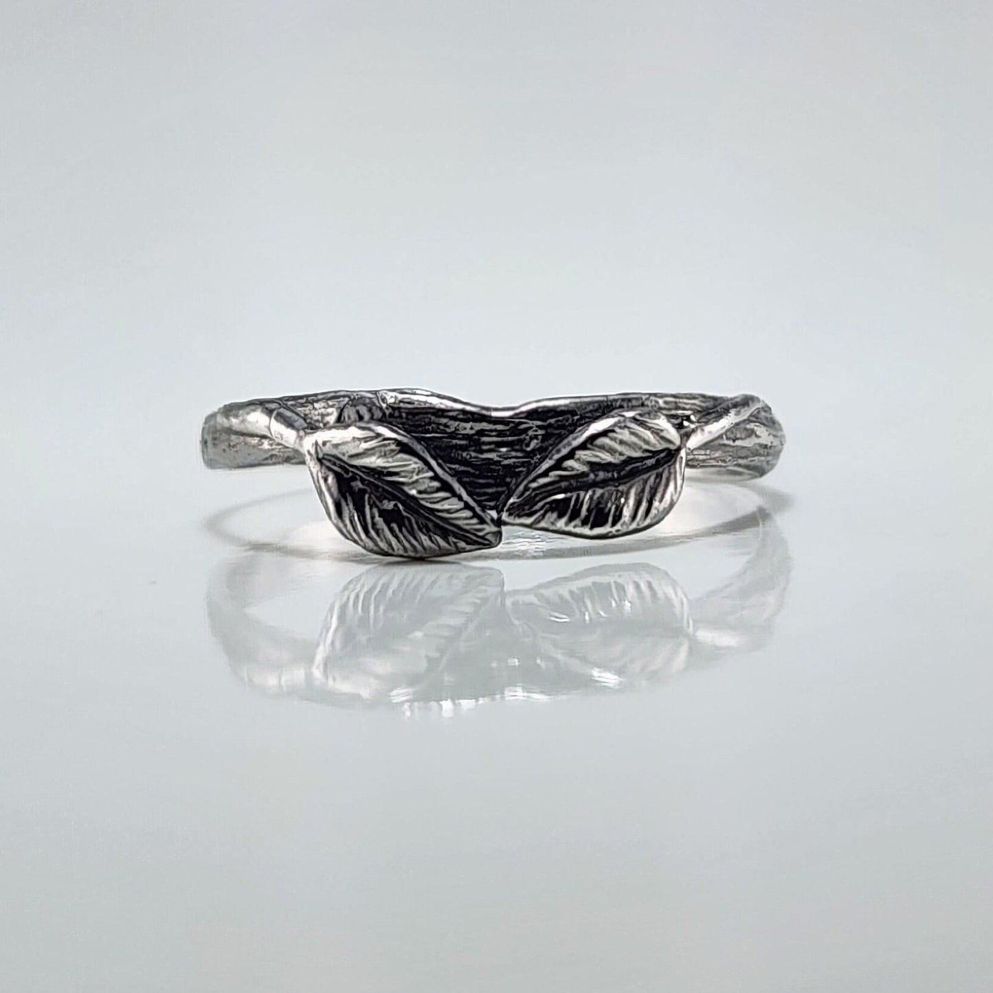Silver ring with leaf design on a light gray background
