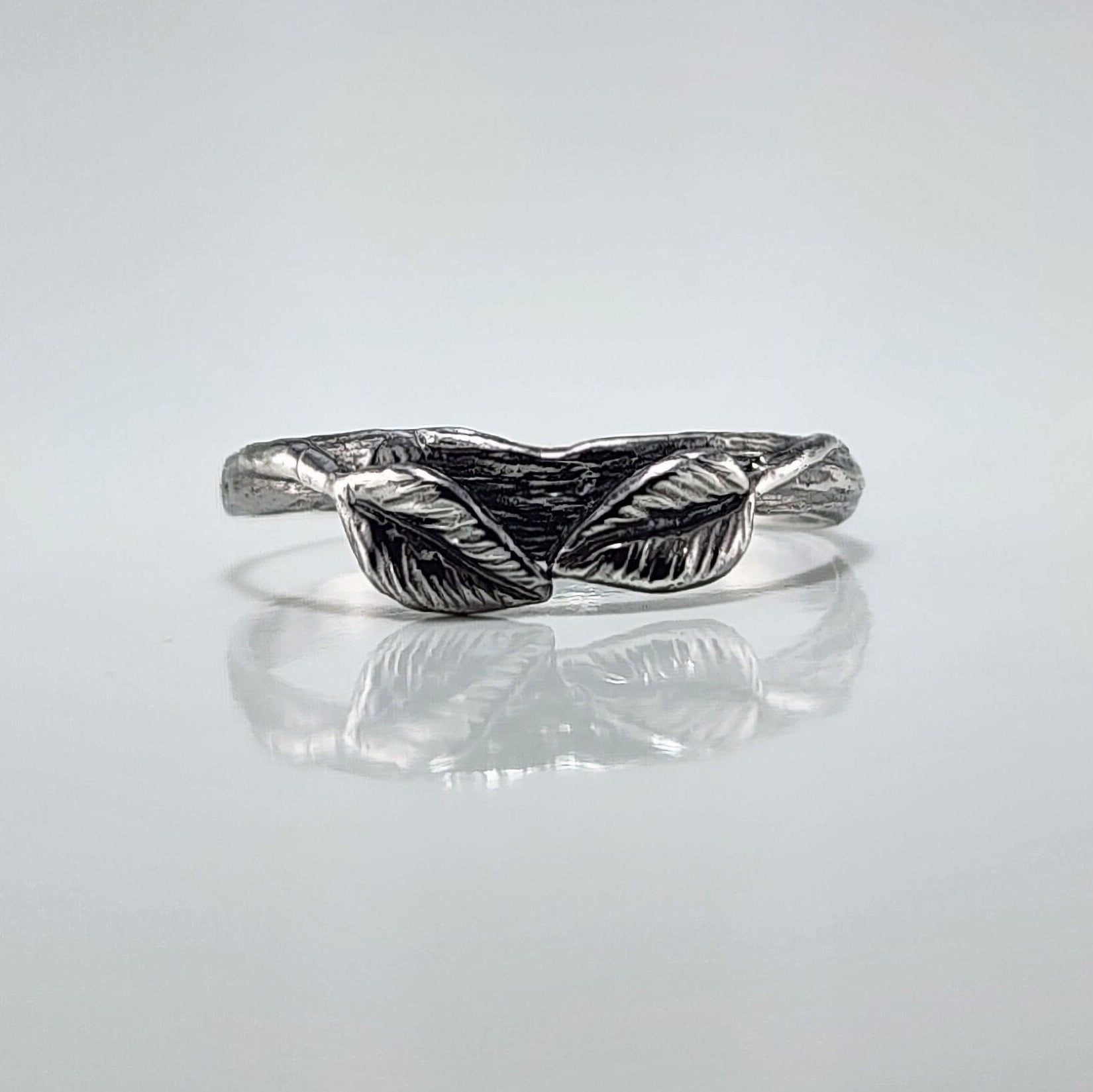Silver ring with leaf design on a light gray background