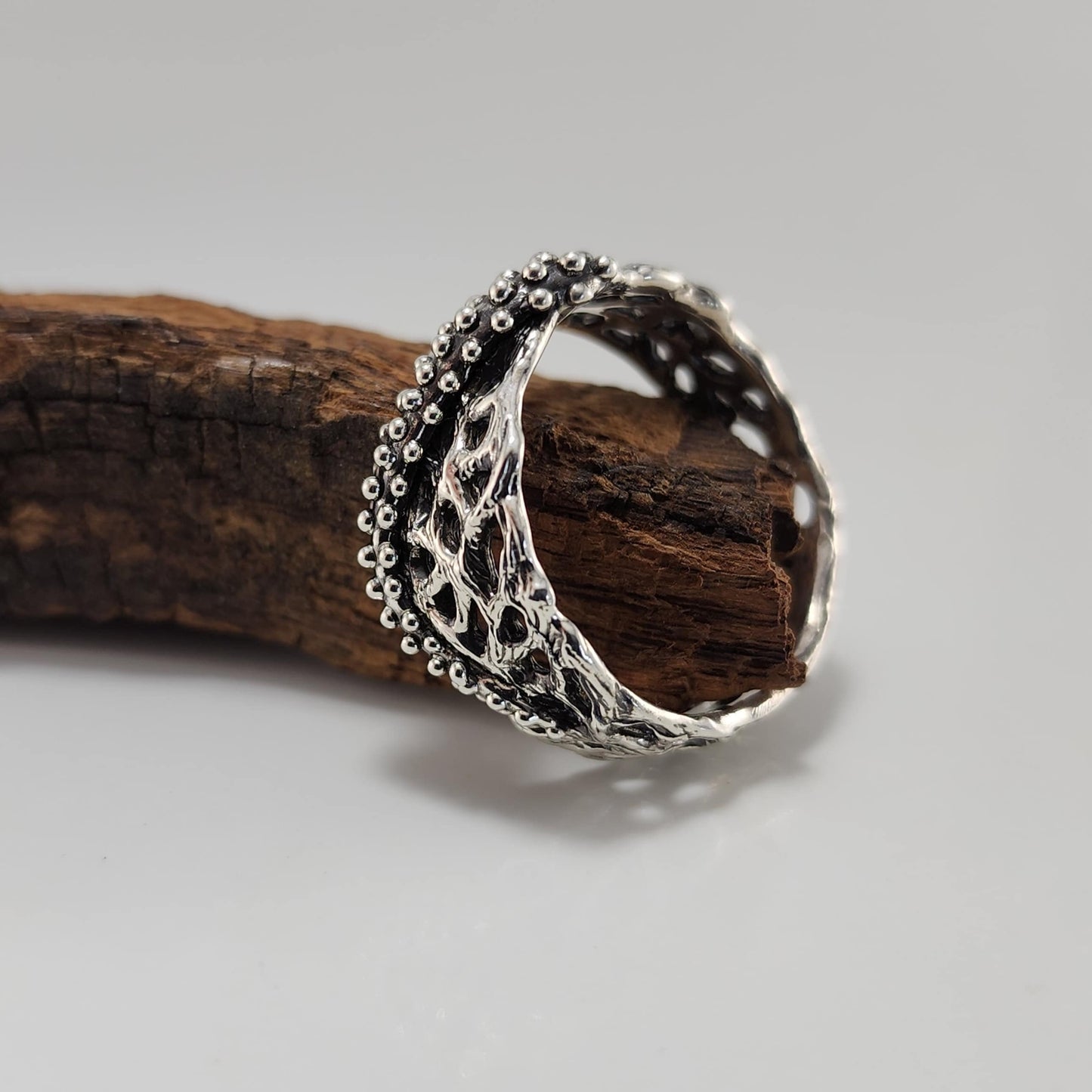 Silver ring with intricate design on a wooden surface
