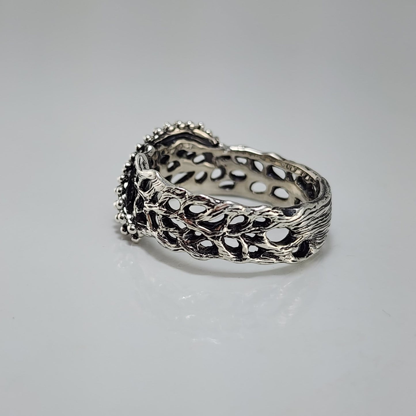 Silver ring with intricate starfish and sea fan coral design on a white background