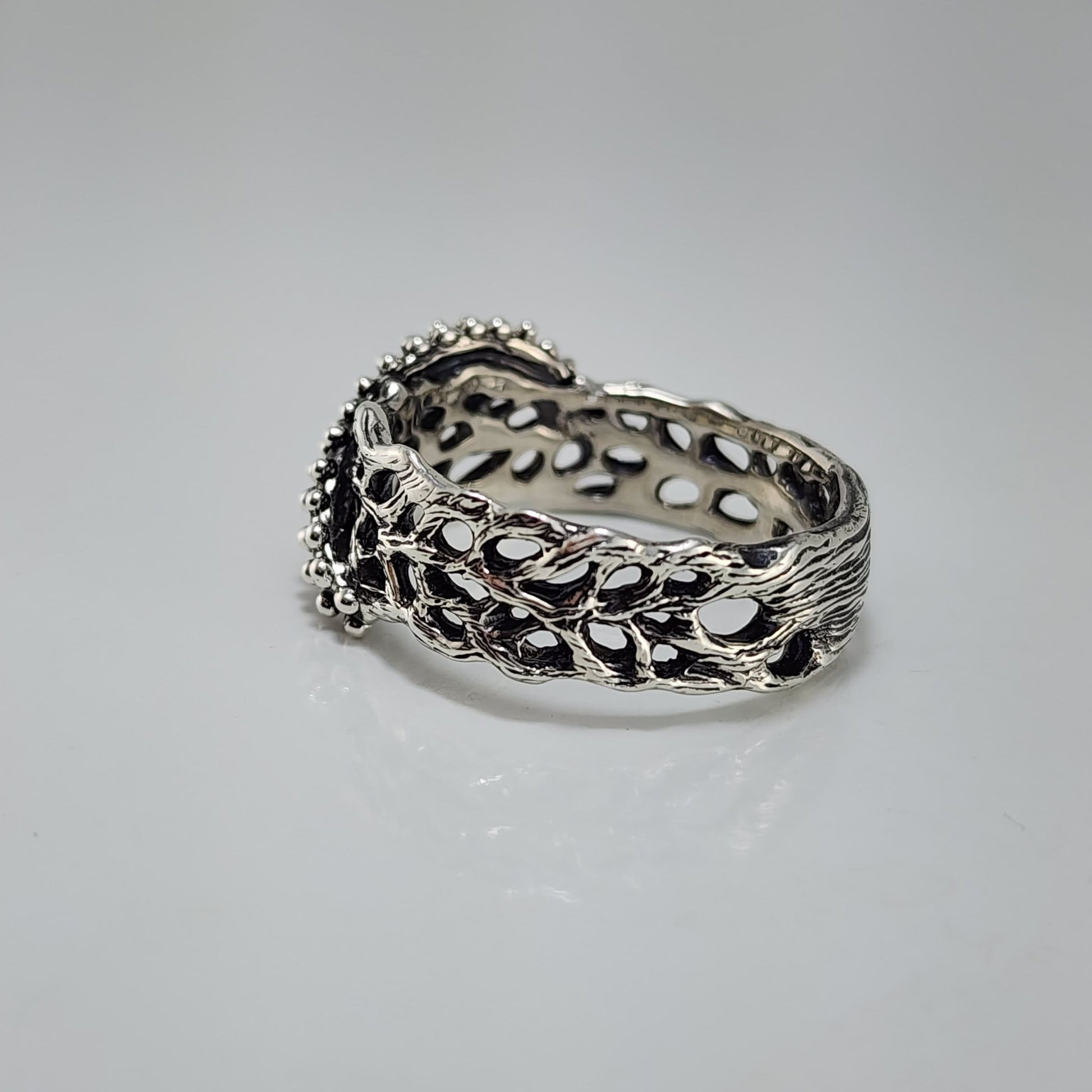 Silver ring with intricate starfish and sea fan coral design on a white background