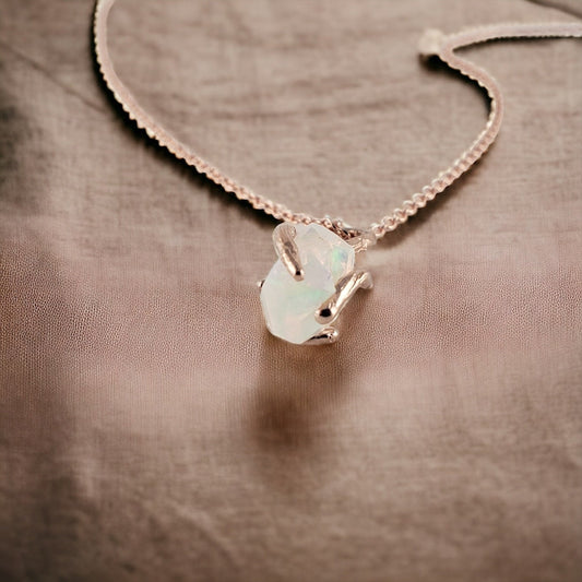 Raw hand-cut opal held by solid gold prongs looking like branches