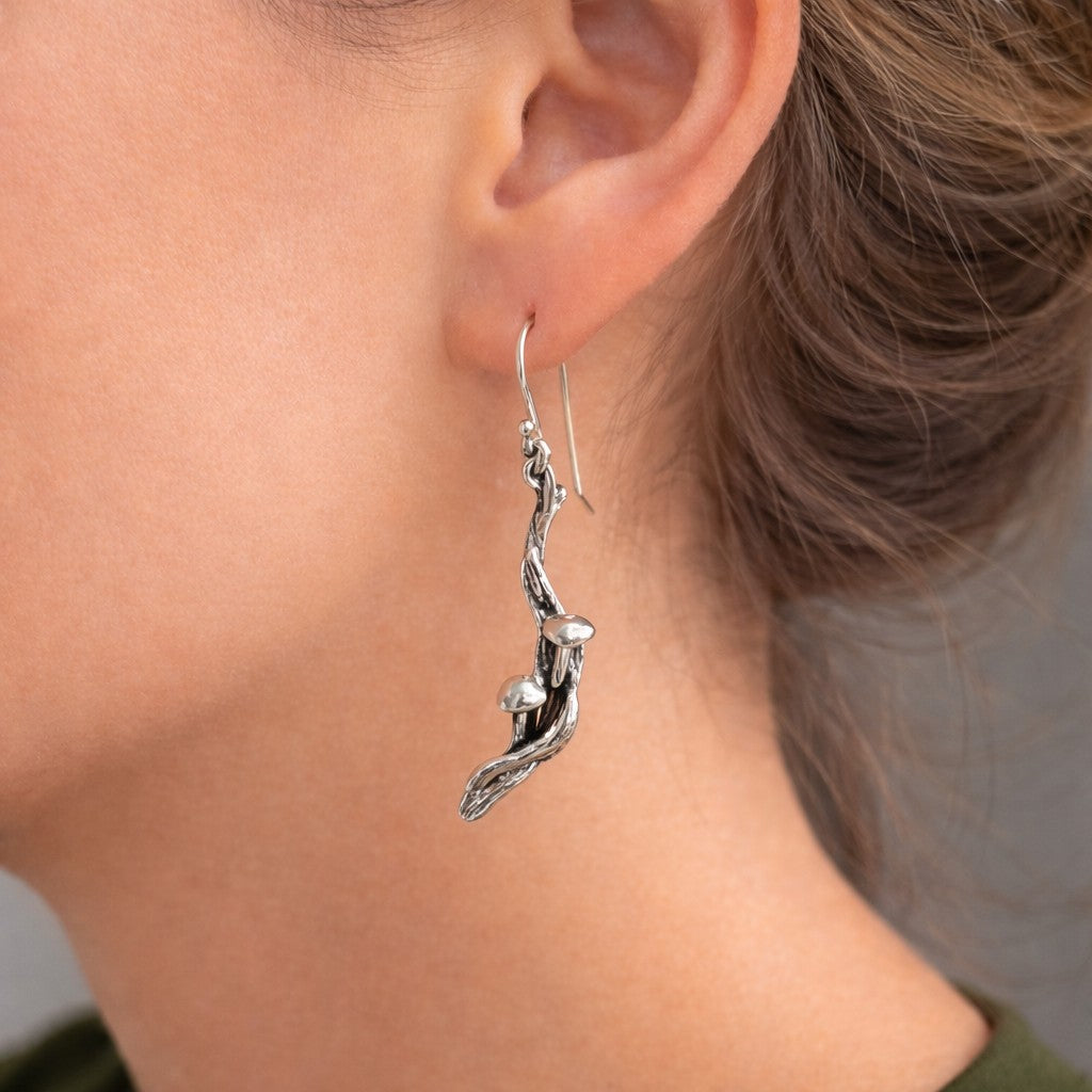Silver branch-shaped earrings with mushrooms on a person