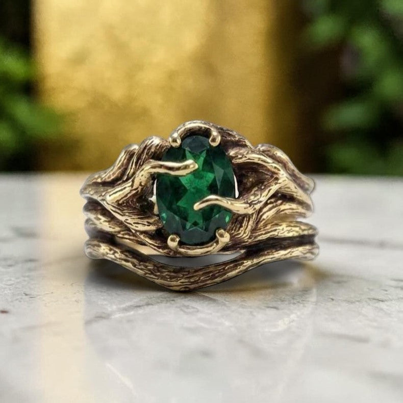 Gold ring with a green gemstone on a marble surface