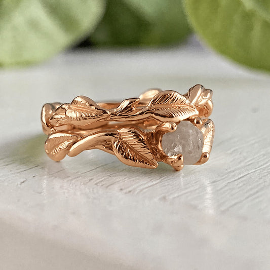 Rose gold ring with leaf design on a light background