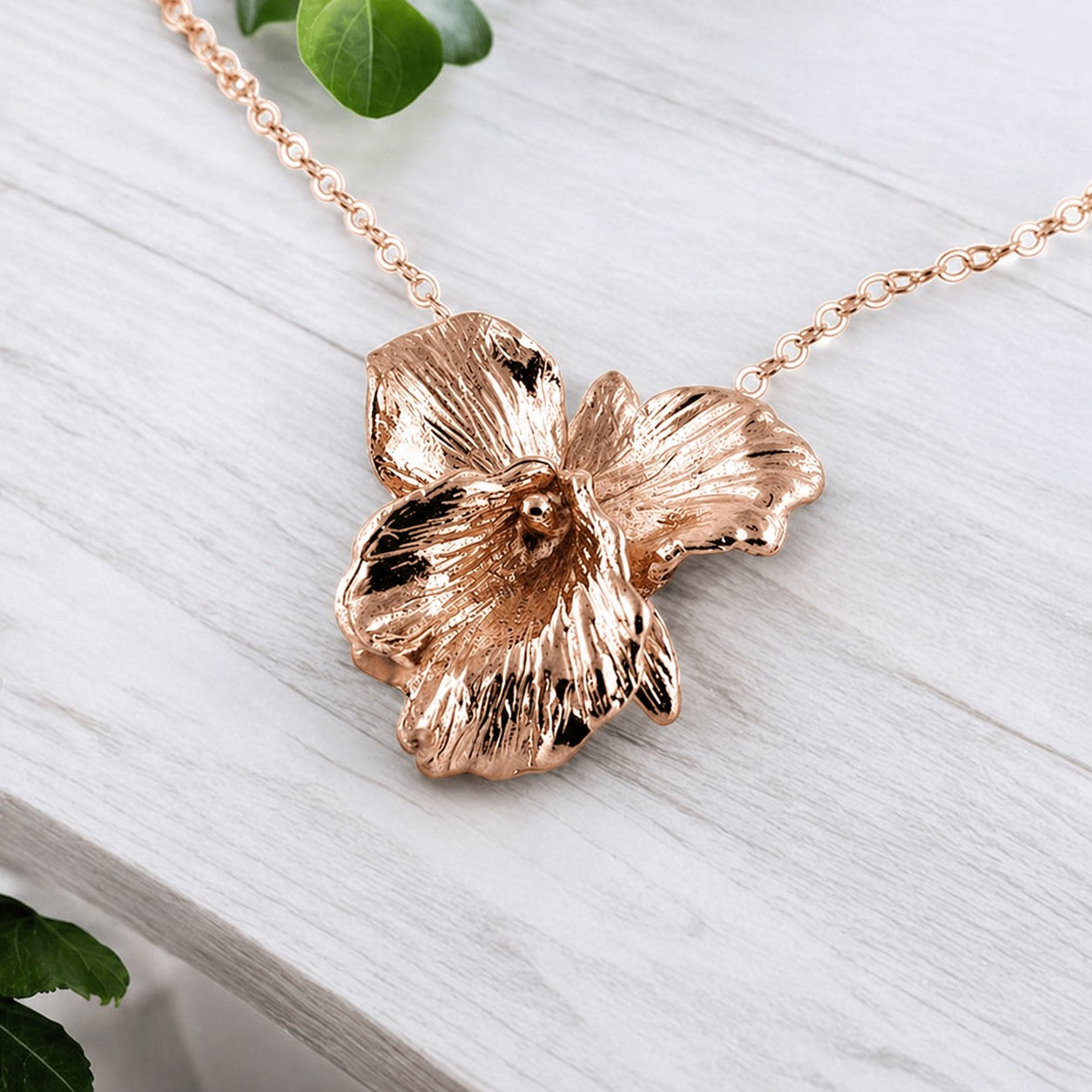 Rose gold flower-shaped necklace on a light wooden surface